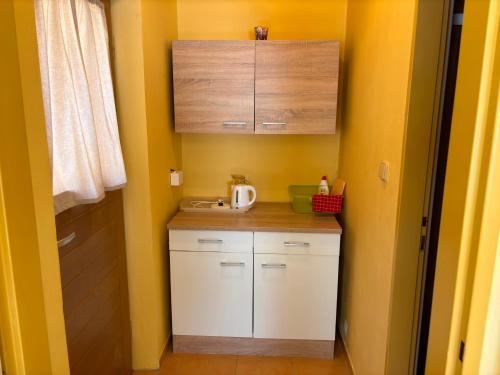 a small kitchen with yellow walls and white cabinets at Penzion U Báby in Třeboň