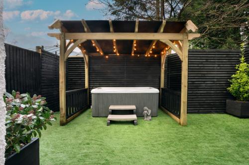a pergola with a table and a bench in a yard at Aphrodites Group - Luxury Hot Tub Suites in Central Lake District! in Bowness-on-Windermere