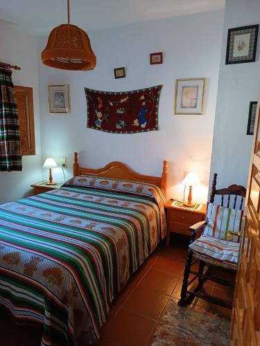 a bedroom with a bed and a chair and lamps at Casa Margarita in Bubión
