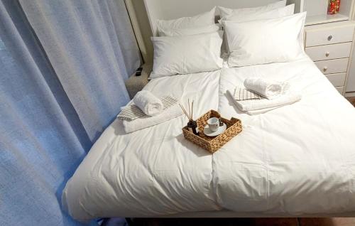 un letto bianco con asciugamani e un cesto di Calm & Comfortable Studio: Central Kalamaria, Walk to the Sea + On-site Parking a Salonicco