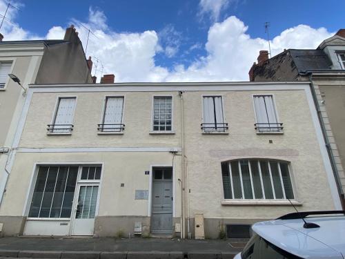 - un bâtiment blanc avec des fenêtres et une porte dans l'établissement Appartements Rue Lemoine XXL, à Angers