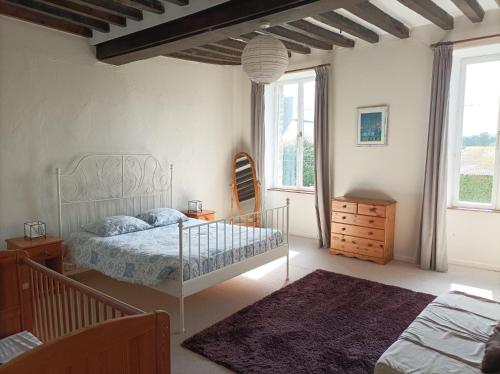 a bedroom with a bed and a dresser and windows at La Petellerie, maison de campagne avec piscine pour un séjour détente in Moyon