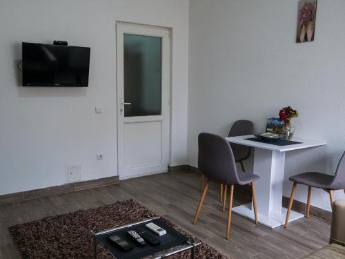 ein Wohnzimmer mit einem Tisch, Stühlen und einem TV in der Unterkunft Cozy spacious apartment in Peja