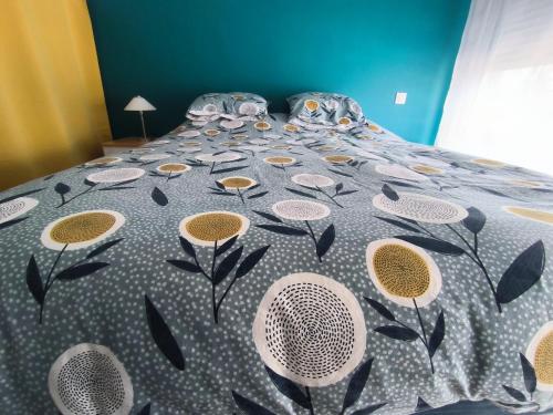 - un lit avec une couette en fleurs dans l'établissement Chambre St Saturnin petit déjeuner compris, à Saint-Saturnin