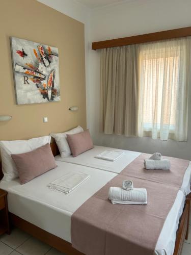 two beds in a hotel room with towels on them at Rosmaris Apartments in Plataniás