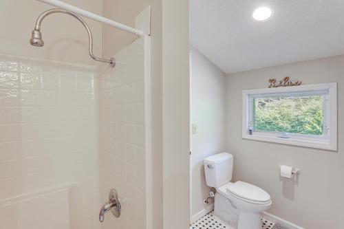 a bathroom with a toilet and a shower and a window at Lake and Pool Access Spacious Home in Newland in Newland