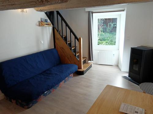 uma sala de estar com um sofá azul e uma escada em Le petit atelier, centre-ville, vue rivière em Villedieu-les-Poëles