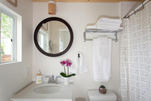 uma casa de banho com lavatório, espelho e toalhas em Stylish 2bed 2bath Culver Cottage with bicycles em Los Angeles