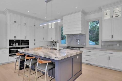 a kitchen with white cabinets and a large island with bar stools at Atl Royal in Atlanta