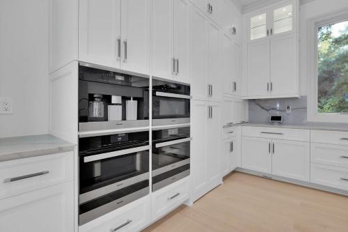 a white kitchen with white cabinets and stainless steel appliances at Atl Royal in Atlanta