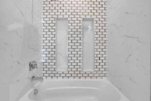 a white bathroom with a mirror and a white tub at Atl Royal in Atlanta
