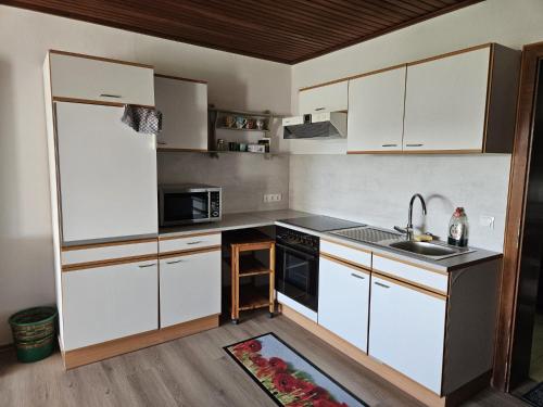 a kitchen with white cabinets and a sink at Unter Linden in Bad Bocklet