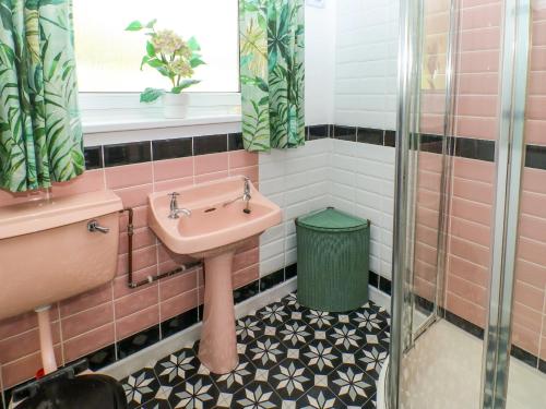 a bathroom with a sink and a green trash can at Jasper's Corner in Kingsbridge