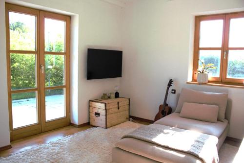 un soggiorno con divano, TV e finestre di Ferienhaus Flying Roots Wackersberg a Wackersberg