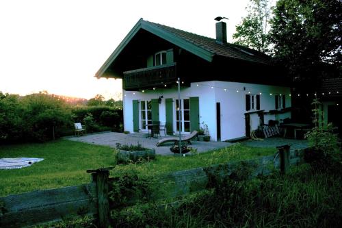 una piccola casa bianca con una recinzione di fronte di Ferienhaus Flying Roots Wackersberg a Wackersberg