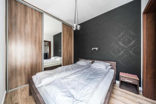 1 dormitorio con cama y pared negra en Apartament Belvedere Ławica Airport, en Poznan