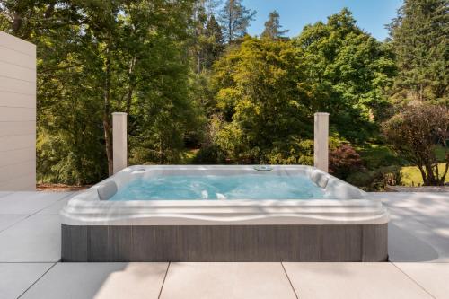 a hot tub on a patio with trees in the background at Aphrodites Group - Luxury Hot Tub Suites in Central Lake District! in Bowness-on-Windermere
