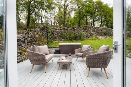 a patio with wicker chairs and a coffee table at Aphrodites Group - Luxury Hot Tub Suites in Central Lake District! in Bowness-on-Windermere