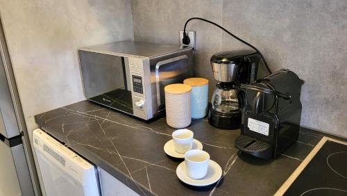 a kitchen counter with a microwave and coffee cups on it at Veta's Luxury apartment near the beach. in Lagonissi