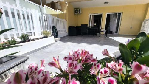 a patio with pink flowers in front of a building at Veta's Luxury apartment near the beach. in Lagonissi