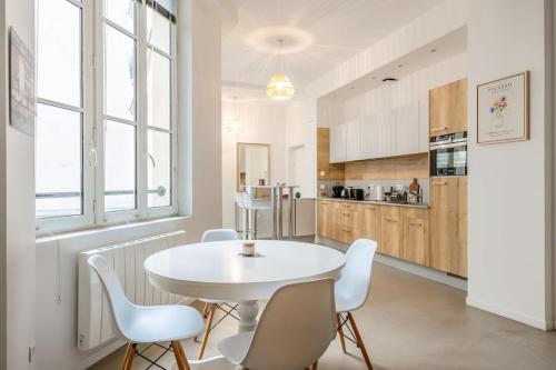 - une cuisine avec une table blanche et des chaises blanches dans l'établissement Superbe Loft 67 m2 Bastille Marais, à Paris