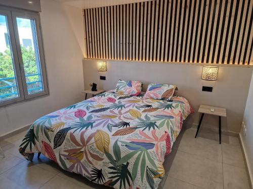 ein Schlafzimmer mit einem Bett mit einer bunten Bettdecke in der Unterkunft Mont-Vert exotique - Calme - Vue et PARKING in Saint-Pierre