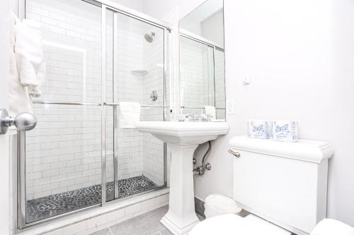 La salle de bains blanche est pourvue d'une douche et d'un lavabo. dans l'établissement Stylish Studio in Boston Brownstone, C.Ave #21, à Boston