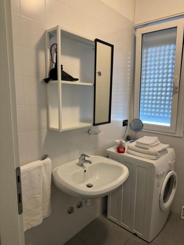 Baño blanco con lavabo y espejo en Appartamenti al Cigno, en Lignano Sabbiadoro