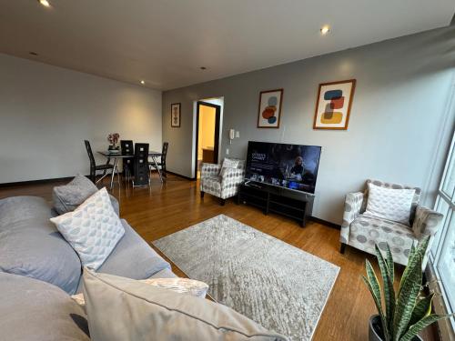a living room with a couch and a flat screen tv at Departamento de Lujo La Carolina - Quicentro Shopping in Quito