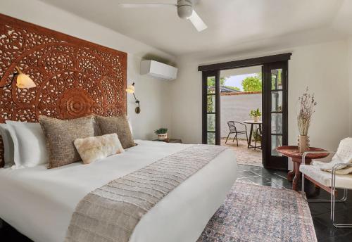 1 dormitorio con 1 cama blanca grande y cabecero de madera en Lucille Palm Springs, en Palm Springs