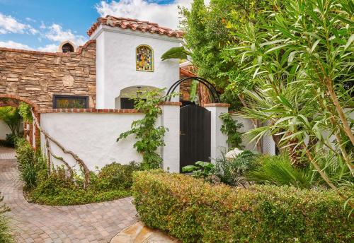 a white house with a black gate and some bushes at Lucille Palm Springs in Palm Springs