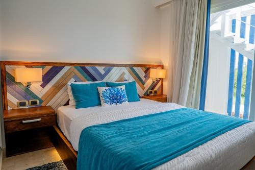 a bedroom with a bed with blue sheets and a window at Xeliter Cana Rock Punta Cana in Punta Cana