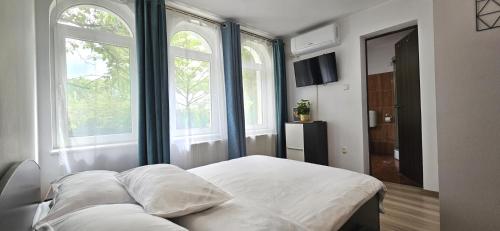 a bed in a room with two large windows at Hillside in Oradea