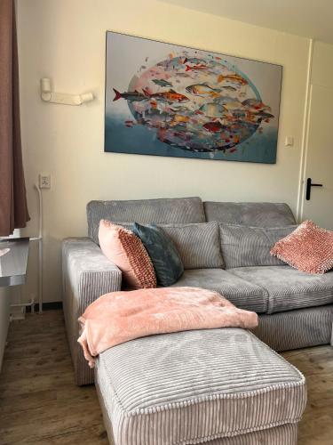 a living room with a gray couch and a painting at Vakantiehuisje Martina 11 in Vlissingen