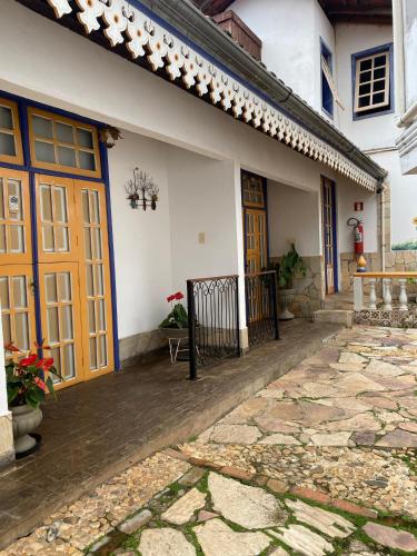 a house with yellow doors and a stone walkway at Pouso das Gerais in Tiradentes