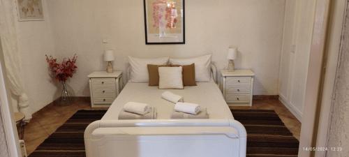 ein Schlafzimmer mit einem großen weißen Bett mit zwei Nachttischen in der Unterkunft Kineta Farmhouse in Kineta