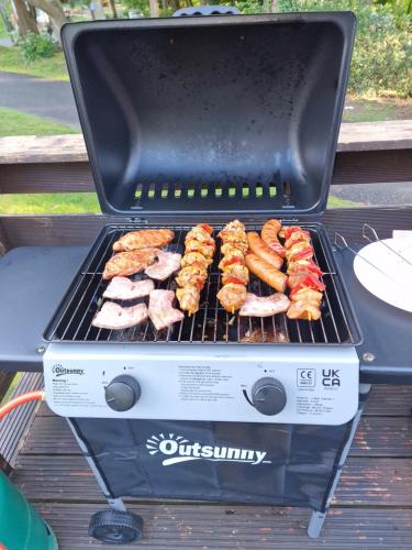 a grill with meat and other food on it at The Forest Cabin Holiday Home 15 in Ballantrae