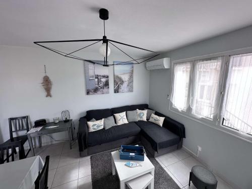 - un salon avec un canapé noir et un lustre dans l'établissement Beau T3 avec terrasse, proche du centre, climatisé, à 10 min des Thermes - Balaruc-les-Bains - FR-1-503-136, à Balaruc-les-Bains