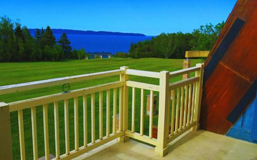 a wooden balcony with a view of the water at Hébergement Fort Prével in Saint-Georges-de-Malbaie