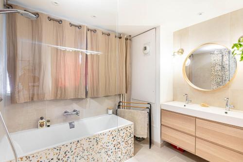 une salle de bain avec une baignoire, un lavabo et un miroir dans l'établissement GuestReady - Skyline serenity near famous hotspots, à Paris