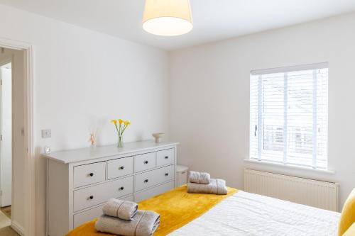 a white bedroom with a bed and a dresser at Limeslade House in Mumbles - Family & Dog Friendly in The Mumbles