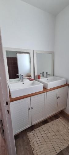 deux lavabos dans une salle de bain avec deux miroirs dans l'établissement Gîte avec piscine vue sur Montcuq, à Saint-Daunès