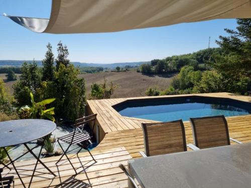 une terrasse avec une piscine, une table et des chaises dans l'établissement Gîte avec piscine vue sur Montcuq, à Saint-Daunès