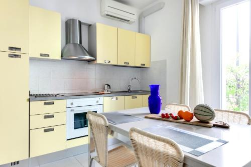 una cocina con armarios blancos y una mesa con sillas. en Residence Diffuso Arcobaleno, en Gabicce Mare