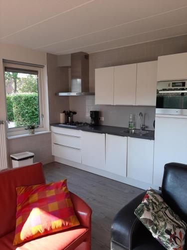 a kitchen with white cabinets and a red couch at libelle in Sint Nicolaasga