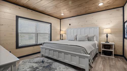 a bedroom with a white bed in a room with wooden walls at Royce' s Retreat in Sevierville