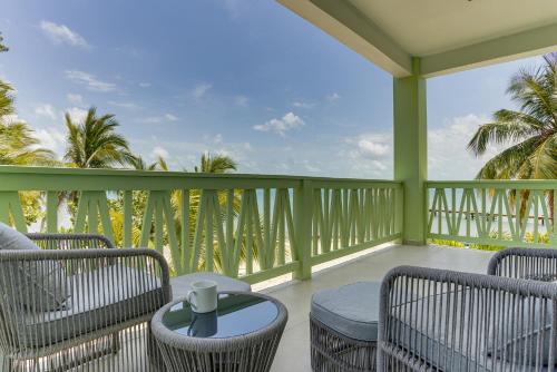 a balcony with chairs and a table and palm trees at The Villas at Cocoplum in Placencia Village