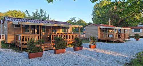 une grande maison en bois avec des plantes en pot devant elle dans l'établissement Mobile home Viareggio - including airco- Camping Paradiso - G008, à Viareggio
