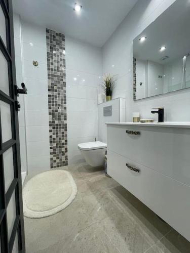 a white bathroom with a toilet and a sink at Sia Bungalow Sunset View in Adeje