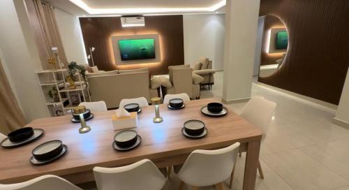 Hotel Apartment - 12 - LAvner Al Moteab في الرياض: غرفة طعام مع طاولة خشبية وكراسي بيضاء
